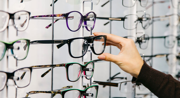 Hand taking a pair of glasses from a wall of frames